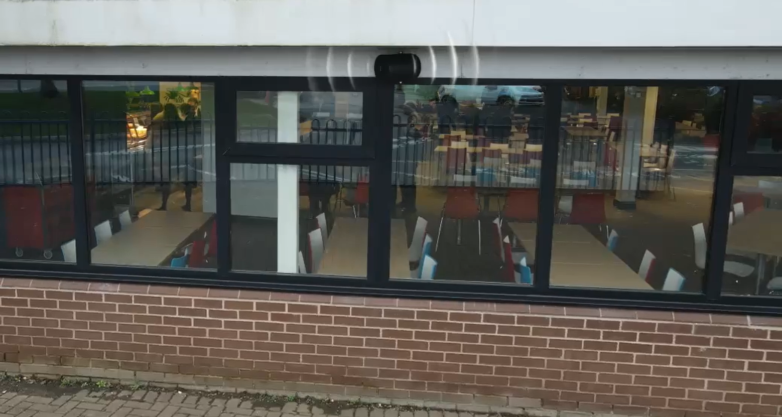 Exterior view of a speaker on the canteen building at Blessed Carlo Acutis School, with students visible through the window.