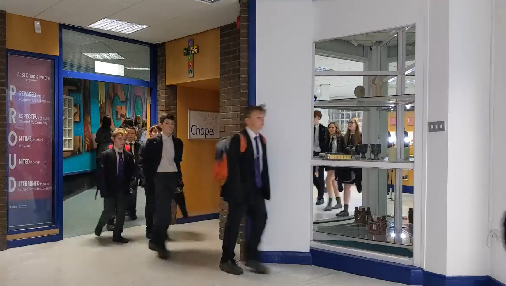 Younger students of Blessed Carlo Acutis School walking down the corridor during class changeover.